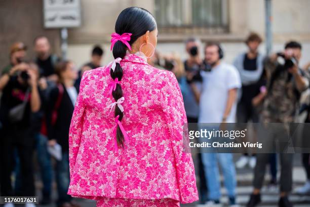 Jaime Xie seen with bows in her hair wearing pink jacket and pants with floral print outside the Blumarine show during Milan Fashion Week...