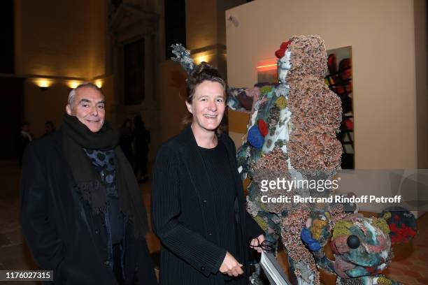 Architect Dominique Perrault and Gaelle Lauriot-Prevost pose with a work of artist Damien Hirst, "The Collector with Friends" during the Kering...