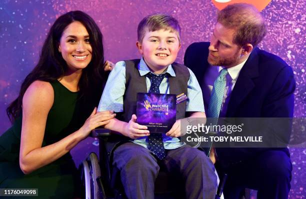 Britain's Prince Harry, Duke of Sussex, and Britain's Meghan, Duchess of Sussex pose for a photograph with award winner William Magee during the...
