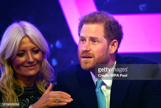Prince Harry, Duke of Sussex reacts next to television presenter Gaby Roslin as he delivers a speech during the WellChild awards at Royal Lancaster...
