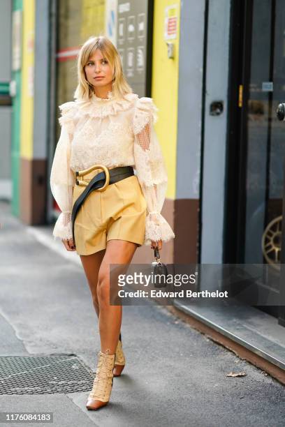 Xenia Adonts wears a white ruffled lace mesh top, a leather belt, a yellow skirt, a Fendi monogram logo brown bag, boots, outside the Marni show...