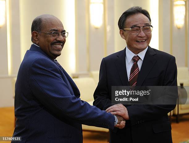 Sudan's leader Omar al-Bashir shakes hands with China's Chairman of the Standing Committee of the National People's Congress Wu Bangguo during their...