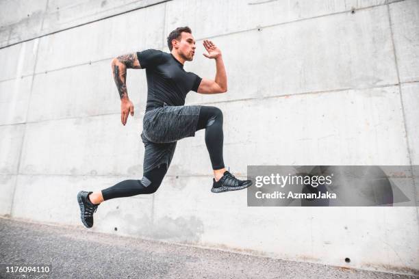 zijaanzicht van sprint mannelijke atleet met voeten van de grond - beenden stockfoto's en -beelden
