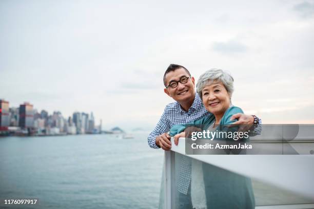 personas de la tercera edad chinas mirando la cámara desde ocean terminal deck - view into land fotografías e imágenes de stock