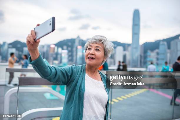 mujer china senior tomando selfie en la cubierta de la terminal del océano - view into land fotografías e imágenes de stock