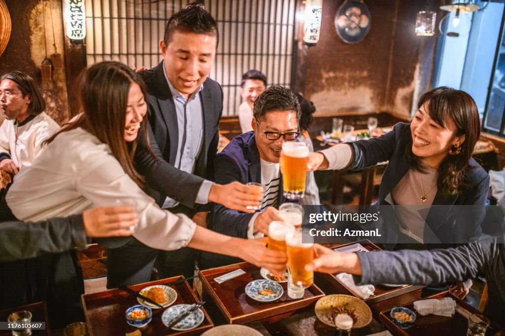 Fun-Loving Japanese Friends Toasting Good News at Izakaya