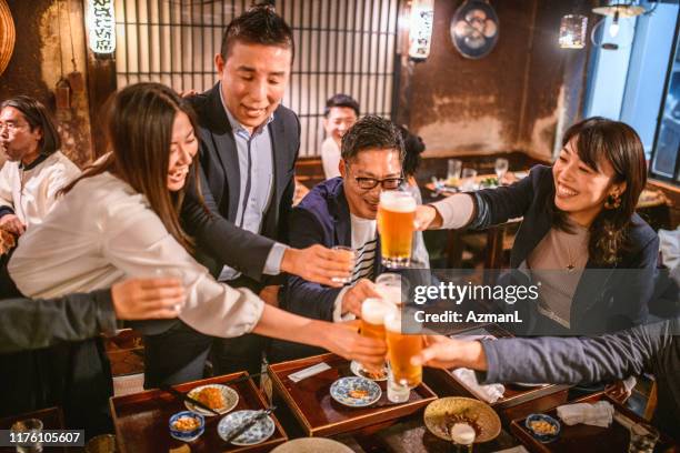 amici giapponesi amanti del divertimento che brindano alle buone notizie a izakaya - happy hour foto e immagini stock