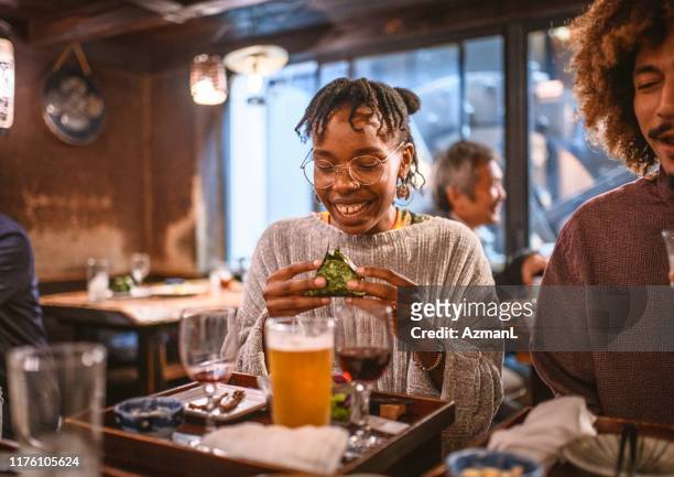 African Woman Drinking Wine and Trying New Food at Izakaya
