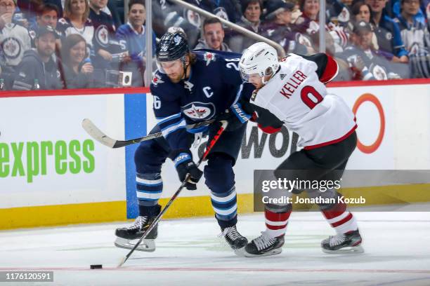 Blake Wheeler of the Winnipeg Jets plays the puck away from Clayton Keller of the Arizona Coyotes during second period action at the Bell MTS Place...