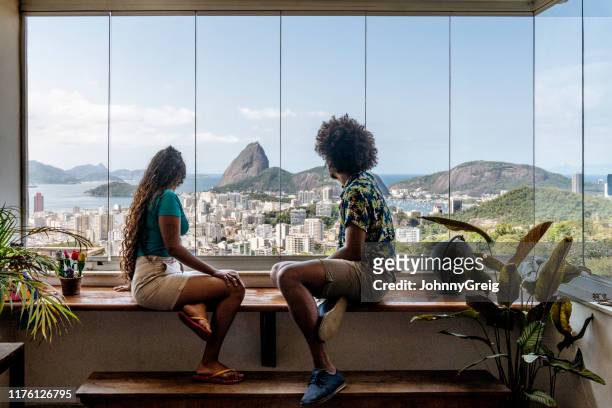 coppia seduta vicino alla finestra e guardando la vista del rio de janiro - monte pan di zucchero foto e immagini stock