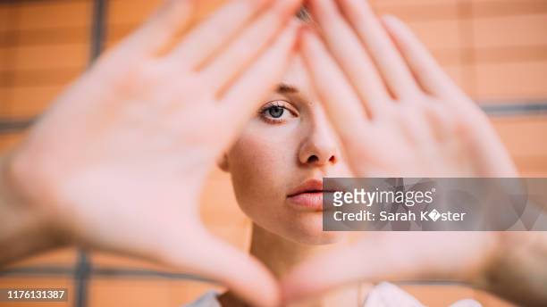 portrait of young woman gesturing over face - viso nascosto foto e immagini stock