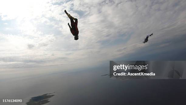 skydivers fall through clear skies, in aerial flight - aerial stunts flying stock pictures, royalty-free photos & images