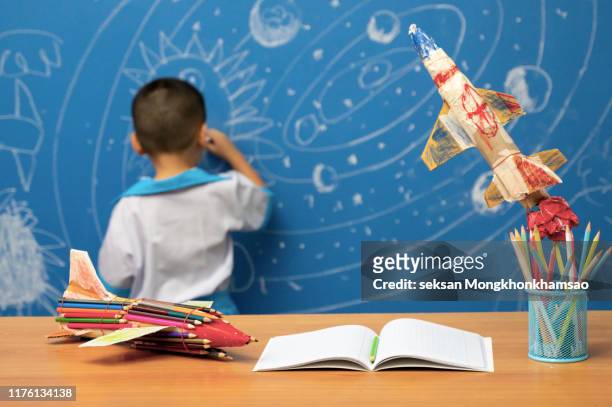 back view of cute kid imagine space travel with set of infographics over textured wall background - better world stockfoto's en -beelden