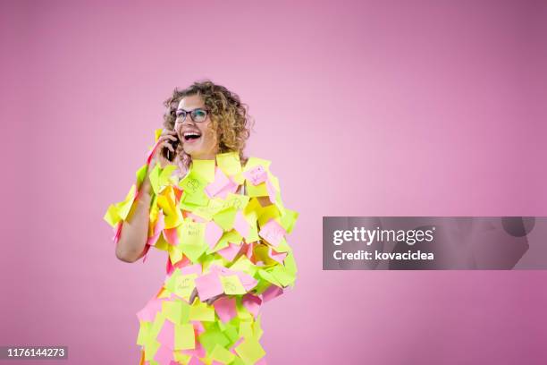 portret van een zakenvrouw op roze achtergrond bedekt met sticky notes met behulp van smart phone - busy woman stockfoto's en -beelden