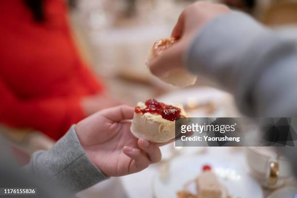people eating the traditional scone with clotted cream and jam - blätterteigbrötchen stock-fotos und bilder