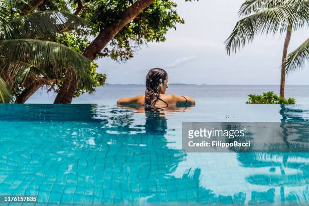 jonge volwassen vrouw ontspannen in een zwembad - bikini atoll stockfoto's en -beelden