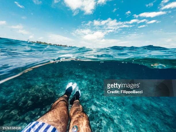 half underwater photo - pov view of legs with fins in a paradisiac sea in maldives - personal perspective view stock pictures, royalty-free photos & images