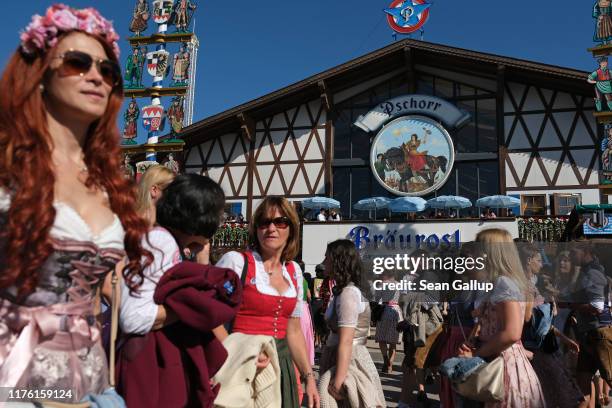 Visitors wearing dirndls walk past a beer tent on the opening day of the 2019 Oktoberfest on September 21, 2019 in Munich, Germany. This year's...