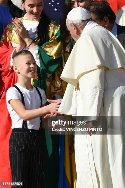 Pope Francis shakes hand with a boy as he meets with members of a circus taking part in an Italian circus festival, during the weekly general...