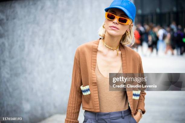 Viktoria Rader, wearing a blue hat, orange Guggi sunglass and brown cardigan, is seen outside the Sportmax show during Milan Fashion Week...