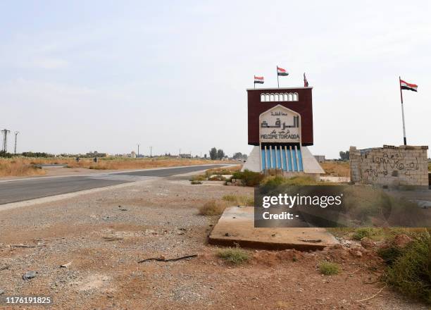 Sign indicating the beginning of the northern Syrian province of Raqa is pictured on October 16, 2019 as Syrian regime forces deployed there at the...
