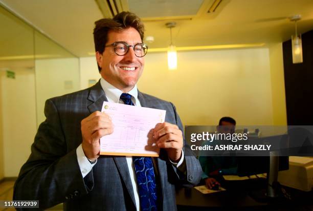 Keith Hughes, Public Affairs Officer at the US Embassy in Khartoum, poses for a picture with a deposit slip after opening an account at a branch of...
