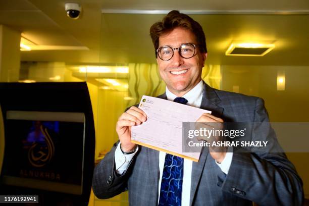 Keith Hughes, Public Affairs Officer at the US Embassy in Khartoum, poses for a picture with a deposit slip after opening an account at a branch of...