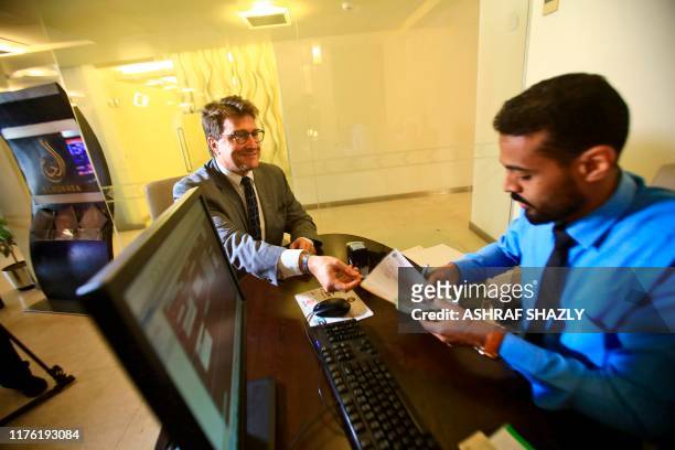 Keith Hughes, Public Affairs Officer at the US Embassy in Khartoum, receives a deposit slip from a clerk as he opens an account at a branch of the...