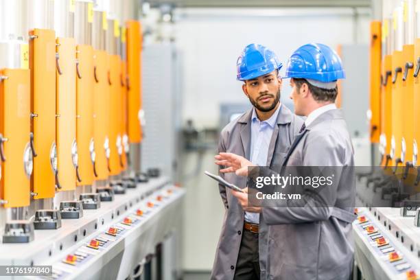 engineers talking while inspecting machinery - industrial worker tablet stock pictures, royalty-free photos & images