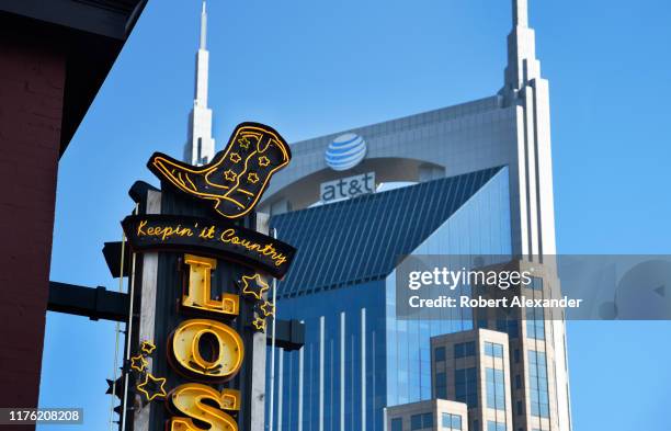 The AT&T skyscraper looms behind a neon sign over the entrance to a Nashville, Tennessee, bar and live country music venue in the city's Lower...