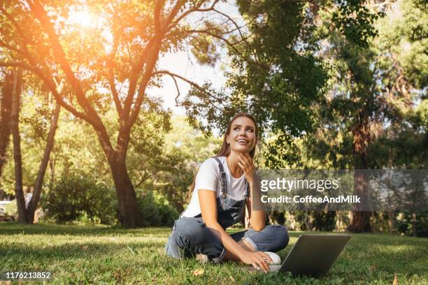 una chica con el portátil sentado en la hierba - laptop netbook fotografías e imágenes de stock