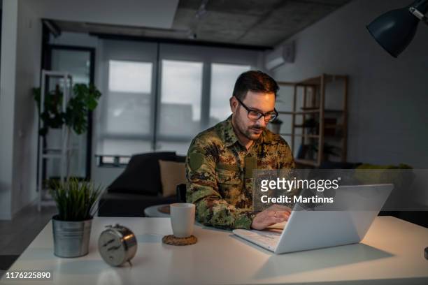 homme d'armée utilisant l'ordinateur portatif à la maison - professional occupation photos et images de collection