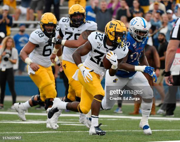 Running back Martell Pettaway of the West Virginia Mountaineers runs for a seven-yard touchdown defensive tackle Jelani Brown of the Kansas Jayhawks...
