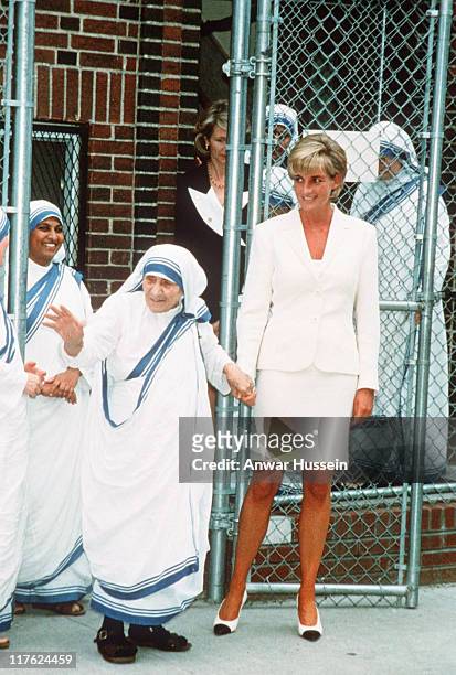 Diana, Princess of Wales, wearing a cream suit, holds hands with Mother Teresa following a meeting in the Bronx on June 18, 1997 in New York, NYC.