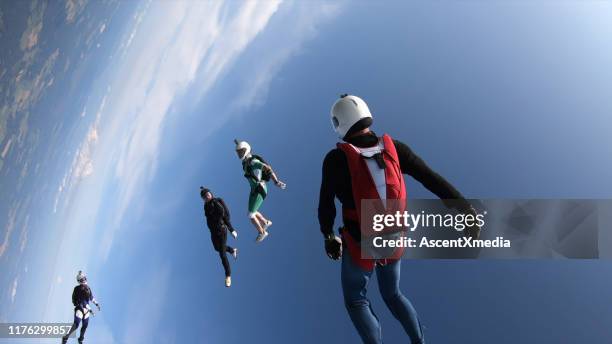 skydivers fall through clear skies, in aerial flight - aerial stunts flying stock pictures, royalty-free photos & images