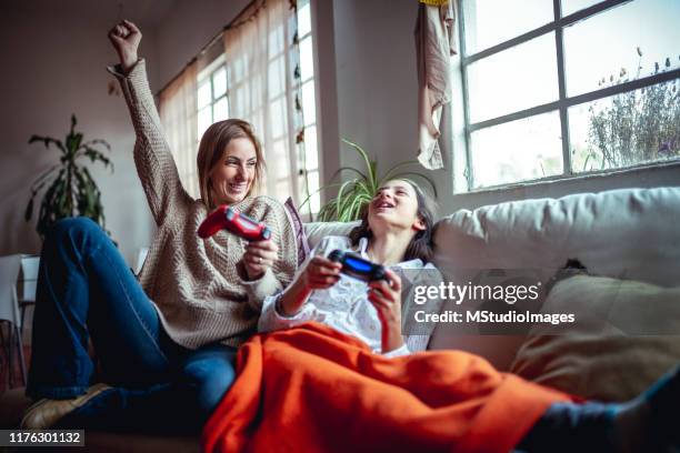 mother and daughter playing video games - brincar imagens e fotografias de stock