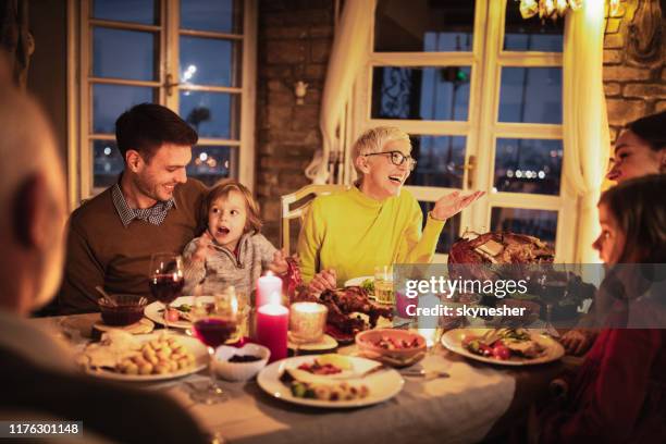 glückliche mehrgenerationenfamilie genießt im gespräch während thanksgiving abendessen am esstisch. - familie essen weihnachten stock-fotos und bilder