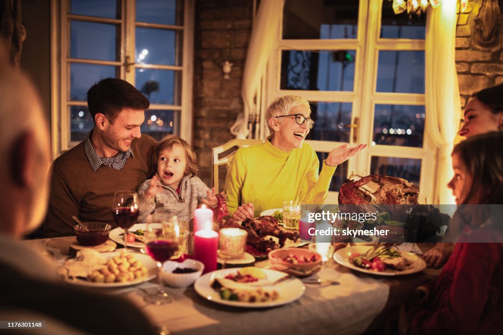 Happy multi-generation family enjoying in conversation during Thanksgiving dinner at dining table.