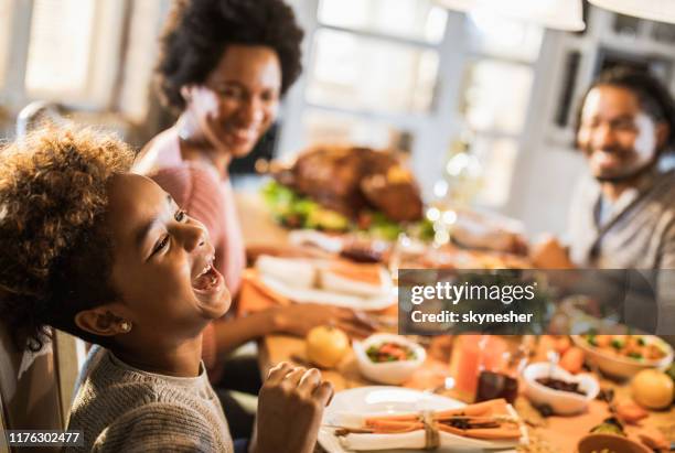 fille afro-américaine gaie avec ses parents à la table à manger. - thanks giving meal photos et images de collection