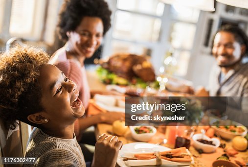 Cheerful African American girl with her parents at dining table. Cheerful African American girl with her parents at dining table.