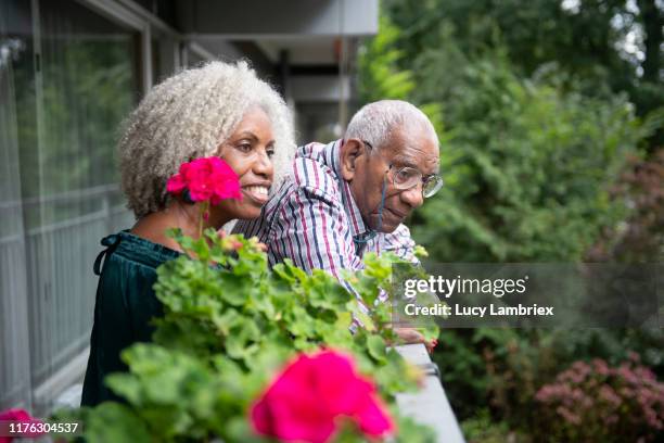91 year old father and his 62 year old daughter standing on his balcony and looking at the surroundings - 63 year old female - fotografias e filmes do acervo