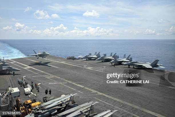 This photograph taken on October 16, 2019 shows a US Navy F/A-18 Super Hornets multirole fighter landing on the flight deck of USS Ronald Reagan...