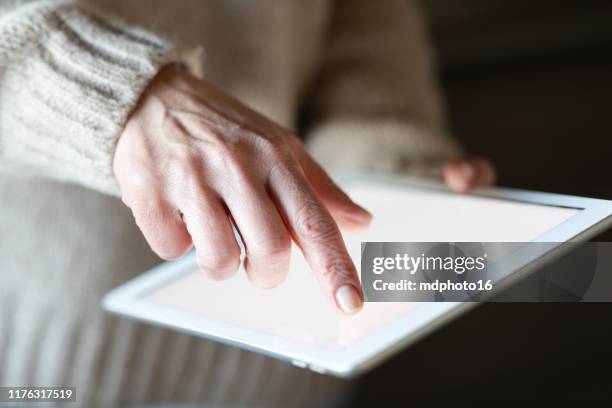 top-ansicht mockup-bild einer seniorin hält schwarze tablet-pc mit leeren weißen desktop-bildschirm - over the shoulder view stock-fotos und bilder