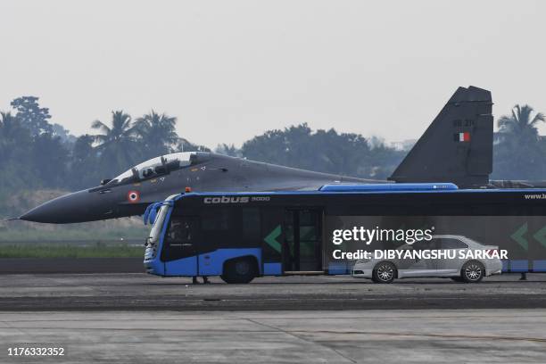 An Indian Air Force Sukhoi Su-30 fighter jet is pictured behind a bus and a car as it takes part in exercises at Netaji Subhas Chandra Bose...