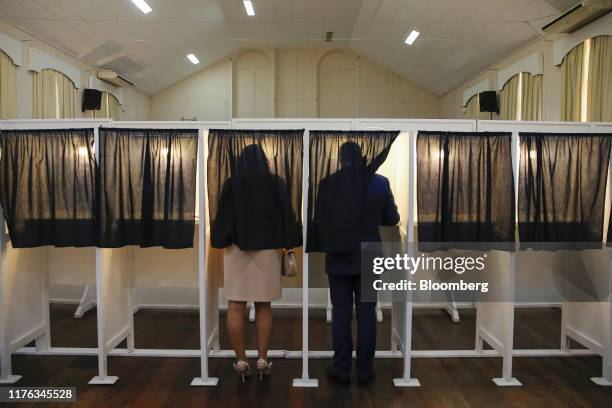 Fabian Picardo, Gibraltar's chief minister and leader of the Socialist Labour Party, right, and his wife Justine, left, stand in booths to cast their...