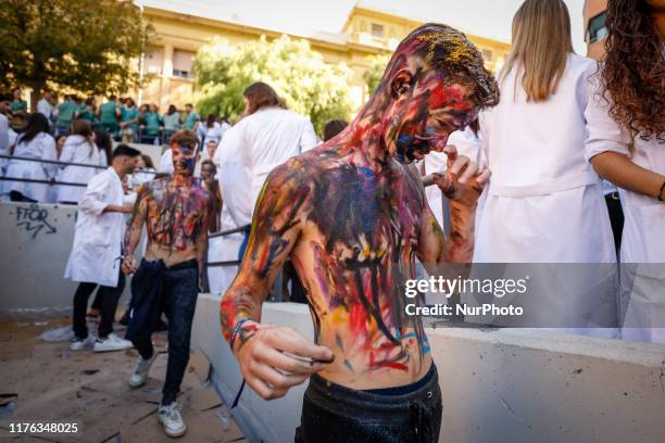 Faculty of medicine first year students walk down a hall while seniors paint them with different color paints and glitter as part of an annual...