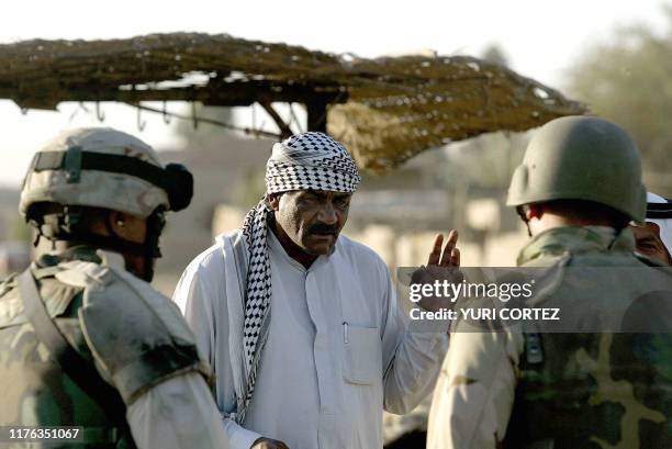 Soldier member of Charlie's Company, 3rd BN 7th Infantry, helped by a translator asks some questions to an Iraqi man during a sweep of a market in...