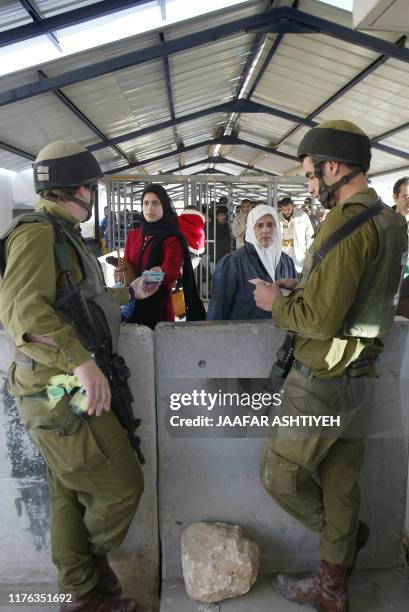 Israeli soldiers check Palestinian women as they cross the Hawara checkpoint near the West Bank city of Nablus, 29 December 2004. Hawara roadblock is...