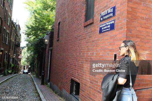 Woman takes a photo of Acorn Street in Boston on Oct. 7, 2019. Acorn Street on Beacon Hill has been dubbed by at least two websites as the "most...