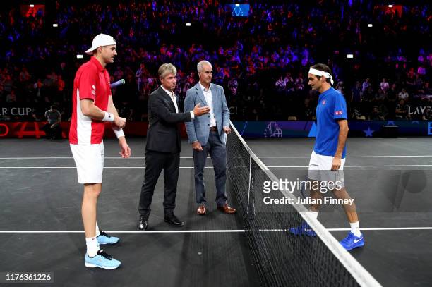 John Isner of Team World and Roger Federer of Team Europe take part in the coin toss with former tennis player Todd Martin prior to their singles...